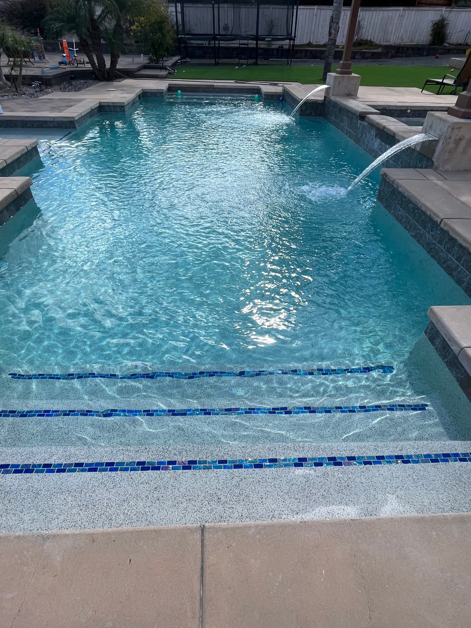 Home repaired concrete pool deck and surrounding clear swimming pool in El Cajon